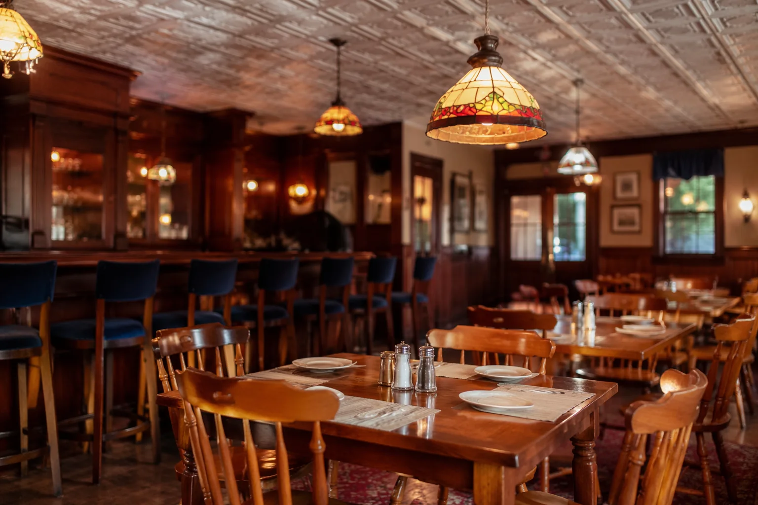 Warm wood-paneled dining room with set tables and a small bar